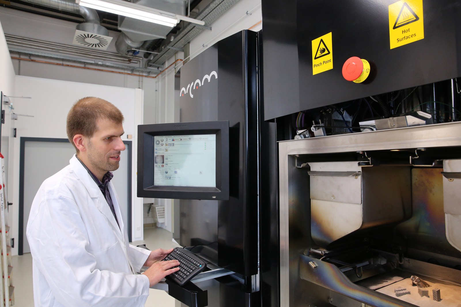 Prof. Dr. Thomas Niendorf vor einem 3D-Metalldrucker (mit älteren Produkten). 