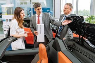 Dr. Dominik Rietzel von BMW (Mitte) erläutert Valentina Kerst, Staatssekretärin im Thüringer Wirtschaftsministerium, und Michael Kynast, Geschäftsführer der Messe Erfurt GmbH, additiv gefertigte Teile am neuen BMW I8 Roadster.
